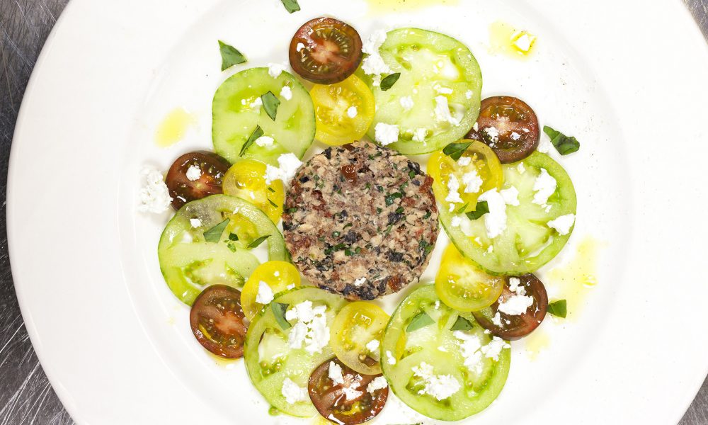 Een frisse tartaar van sardines op een kleurrijk bedje van tomaten