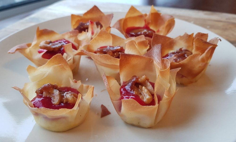 Een elegante borrelhap met smeltende brie, zoete frambozensaus en krokante walnoten