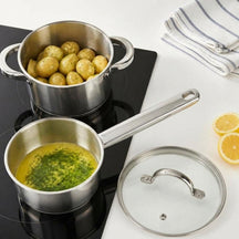 Cooking RVS kookpan met aardappels en steelpan met kruidenboter op inductie, van bovenaf