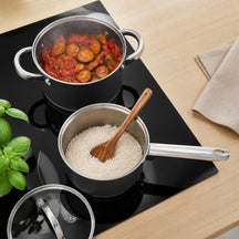 Cooking zwarte kookpan met stoofgroenten en steelpan met rijst op inductie, van bovenaf