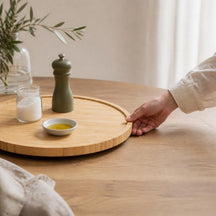 Hand draait het bamboe draaiplateau met zout, pepermolen en olijfolie
