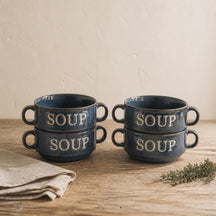 Vier blauwe Soup soepkommen gestapeld in twee stapels op een eiken tafel