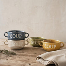 Vier Soup soepkommen in vier kleuren, deels gestapeld, op een eiken tafel