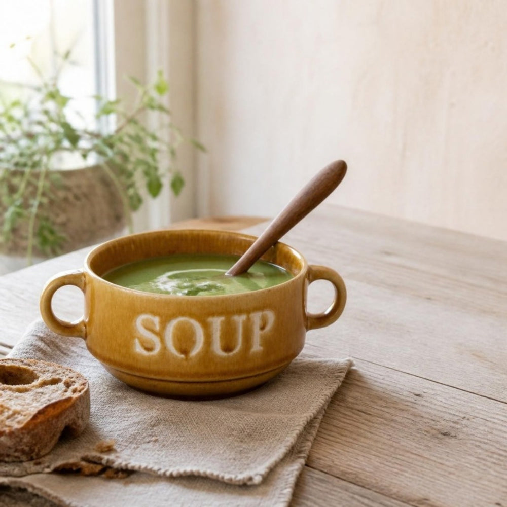 Okergele Soup soepkom met erwtensoep en houten lepel op een linnen servet