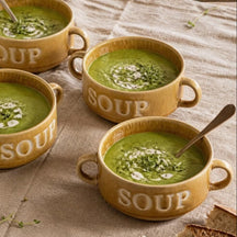 Vier okergele Soup soepkommen met erwtensoep op een gedekte tafel, van bovenaf