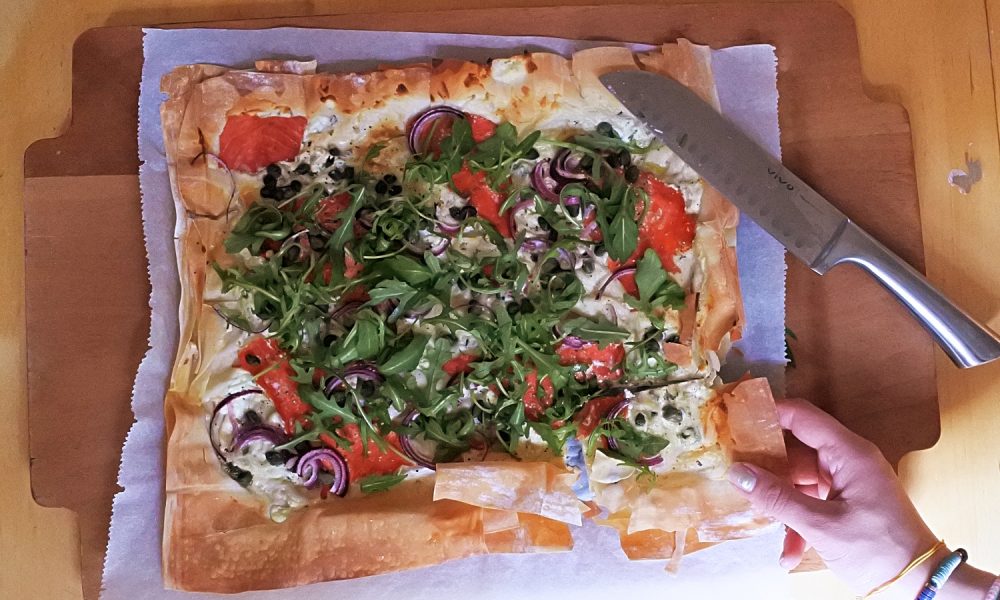 Knapperige plaatpizza met zalm, kruidenkaas en frisse rucola