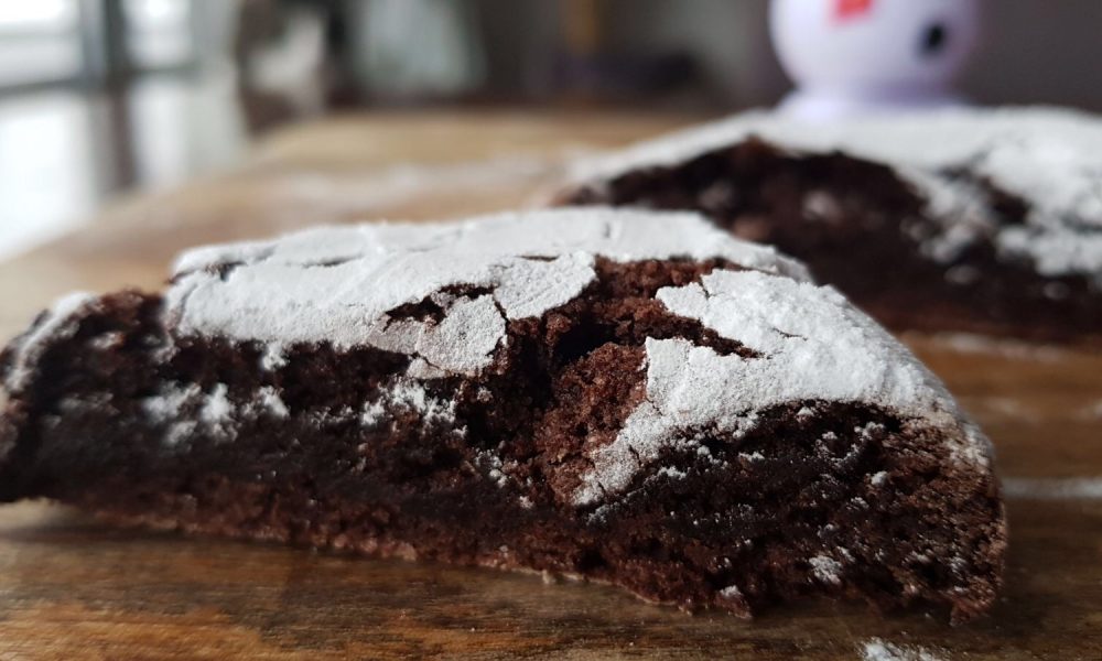 Een grote, fudgy chocoladekoek met een sneeuwwitte laag poedersuiker