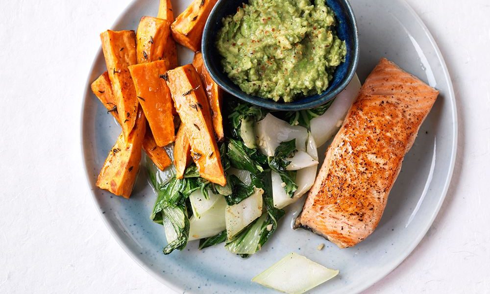 Sappige zalm met romige avocadodip, knapperige paksoi en kruidige zoete aardappelpartjes